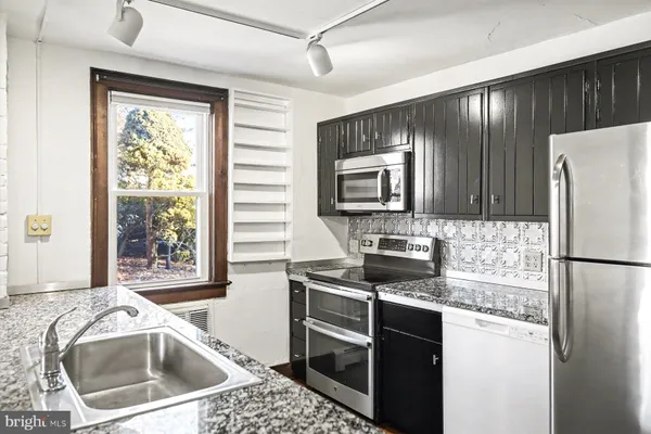 a kitchen with stainless steel appliances granite countertop a refrigerator a stove top oven a sink and dishwasher