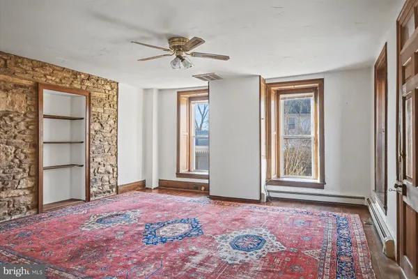 an empty room with windows and ceiling fan