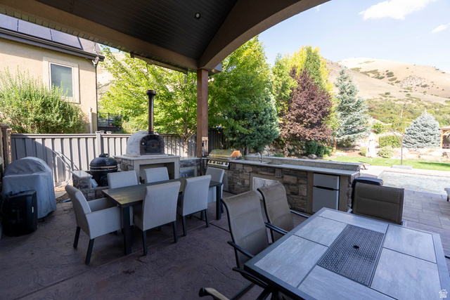 687 South 2080th Street East Springville, UT 84663 - Photo 116 of 149 Covered outdoor patio featuring a built-in pizza oven, stone-clad outdoor kitchen with sink, integrated mini-fridge, and a paved patio area