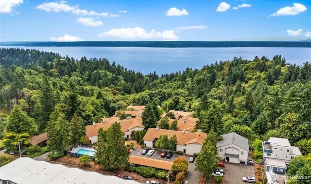 an aerial view of a city with lots of residential buildings ocean and mountain view in back