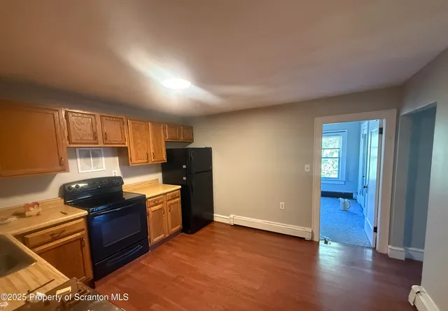 a kitchen with a stove and wooden floor