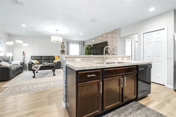 a kitchen with kitchen island granite countertop a sink and a refrigerator