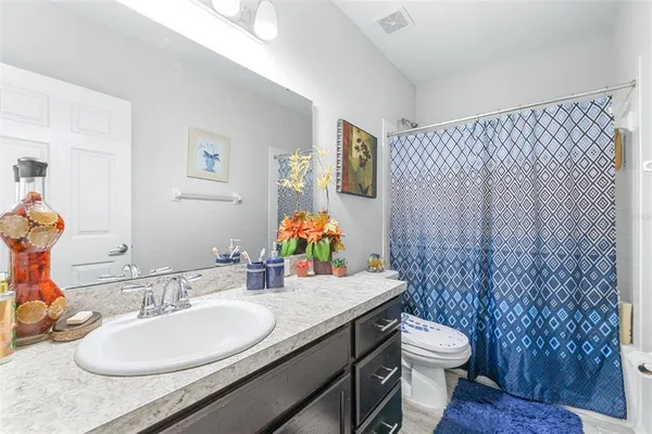 a bathroom with a granite countertop toilet sink and mirror