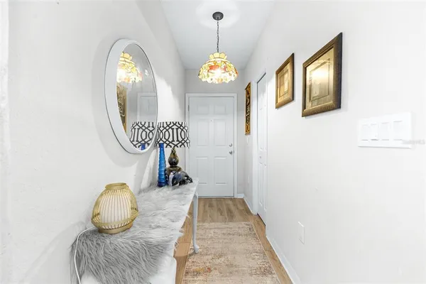 a hallway with painting on the wall and a chandelier