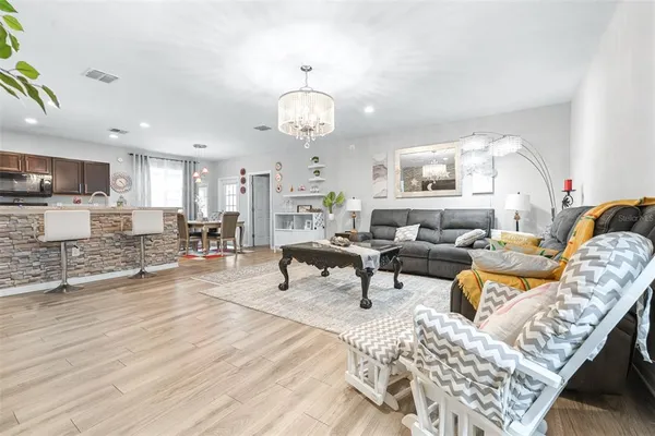 a living room with furniture kitchen view and a chandelier