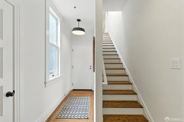 a view of a hallway with front door wooden floor and stairs
