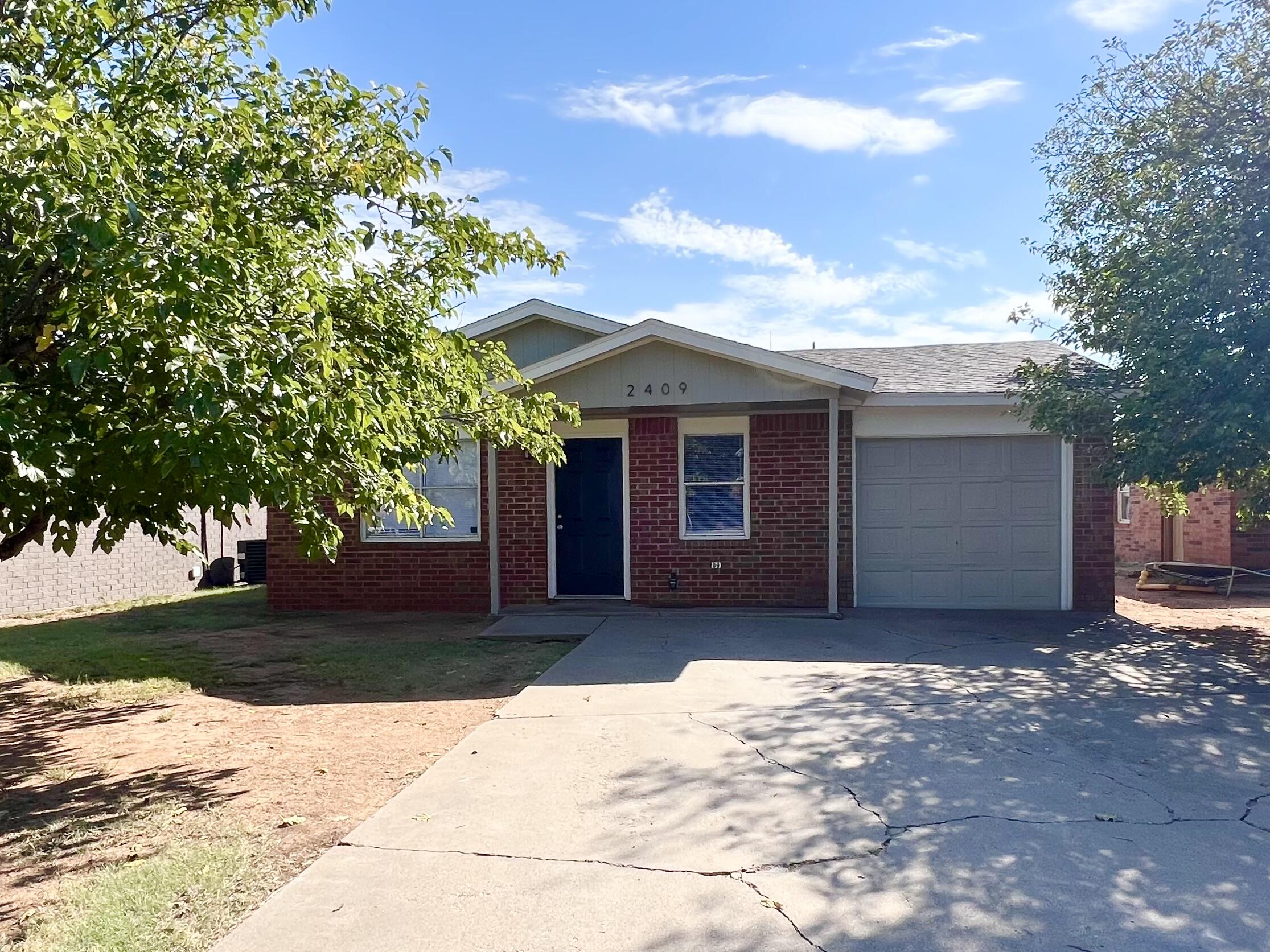2409 88th Street Lubbock, TX 79423 - Photo 1 of 7 a front view of a house with a yard and garage