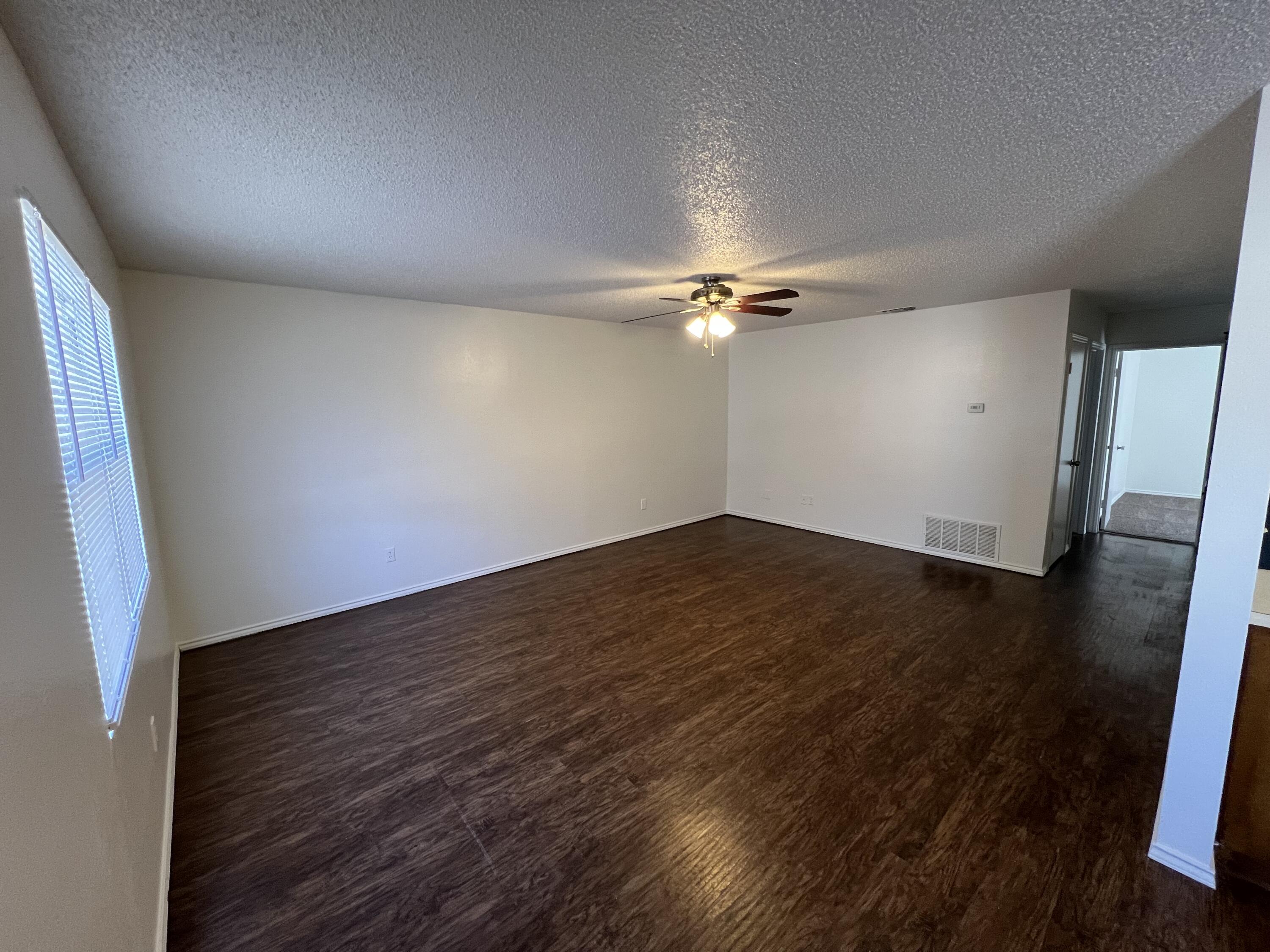 2409 88th Street Lubbock, TX 79423 - Photo 2 of 7 an empty room with wooden floor and chandelier fan