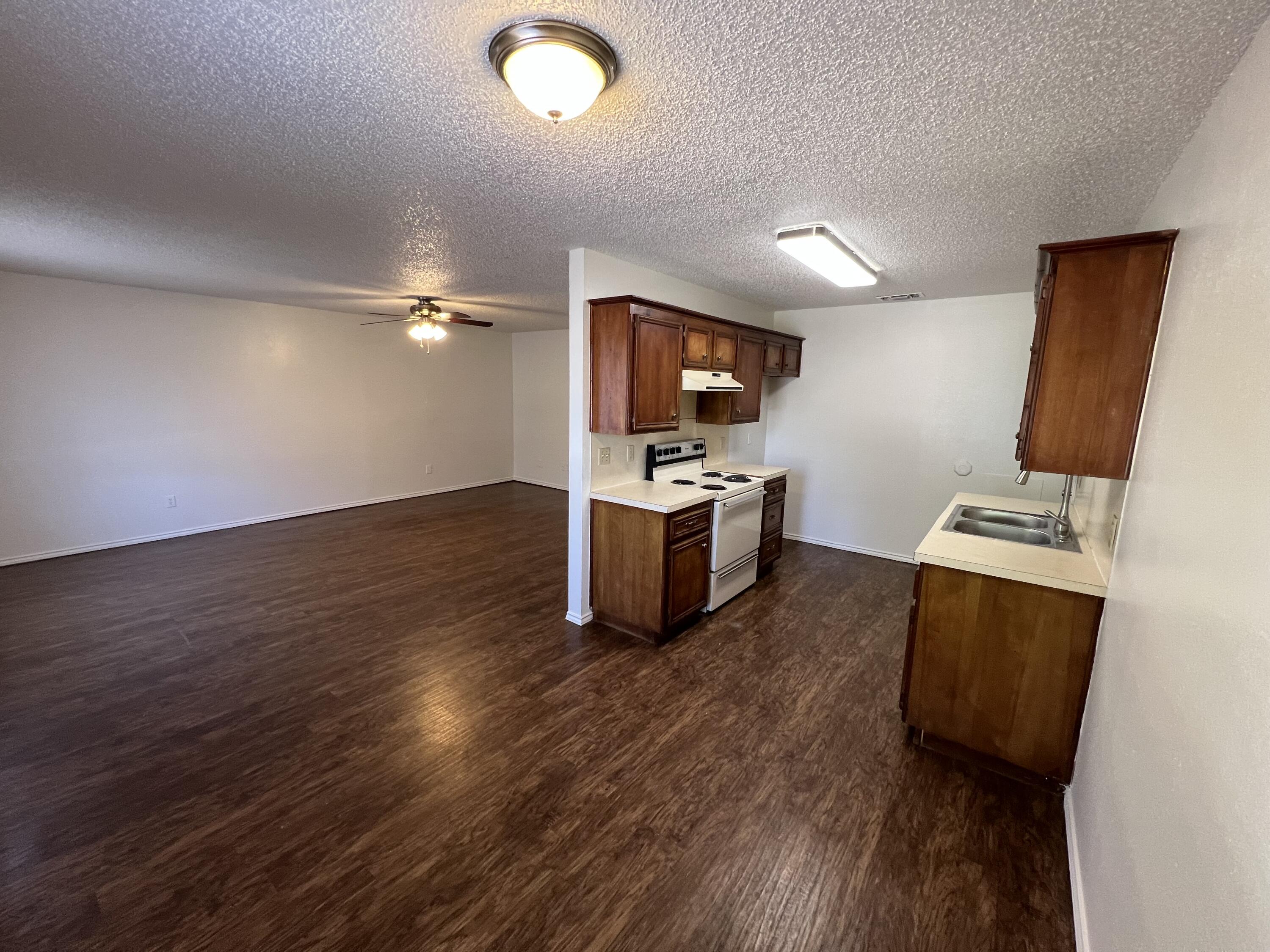 2409 88th Street Lubbock, TX 79423 - Photo 4 of 7 a kitchen with wooden floor and stainless steel appliances