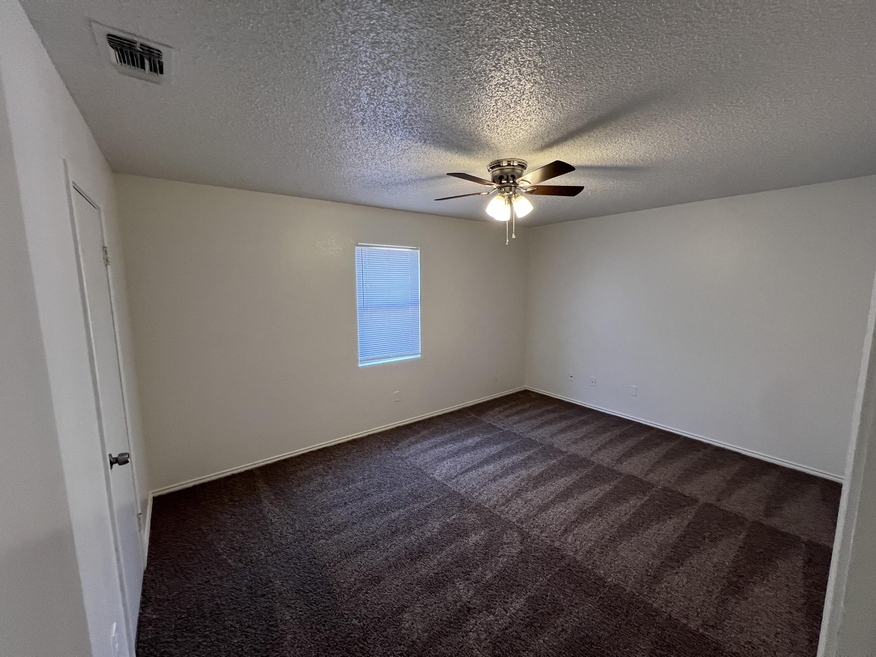 2409 88th Street Lubbock, TX 79423 - Photo 7 of 7 an empty room with a ceiling fan and a window