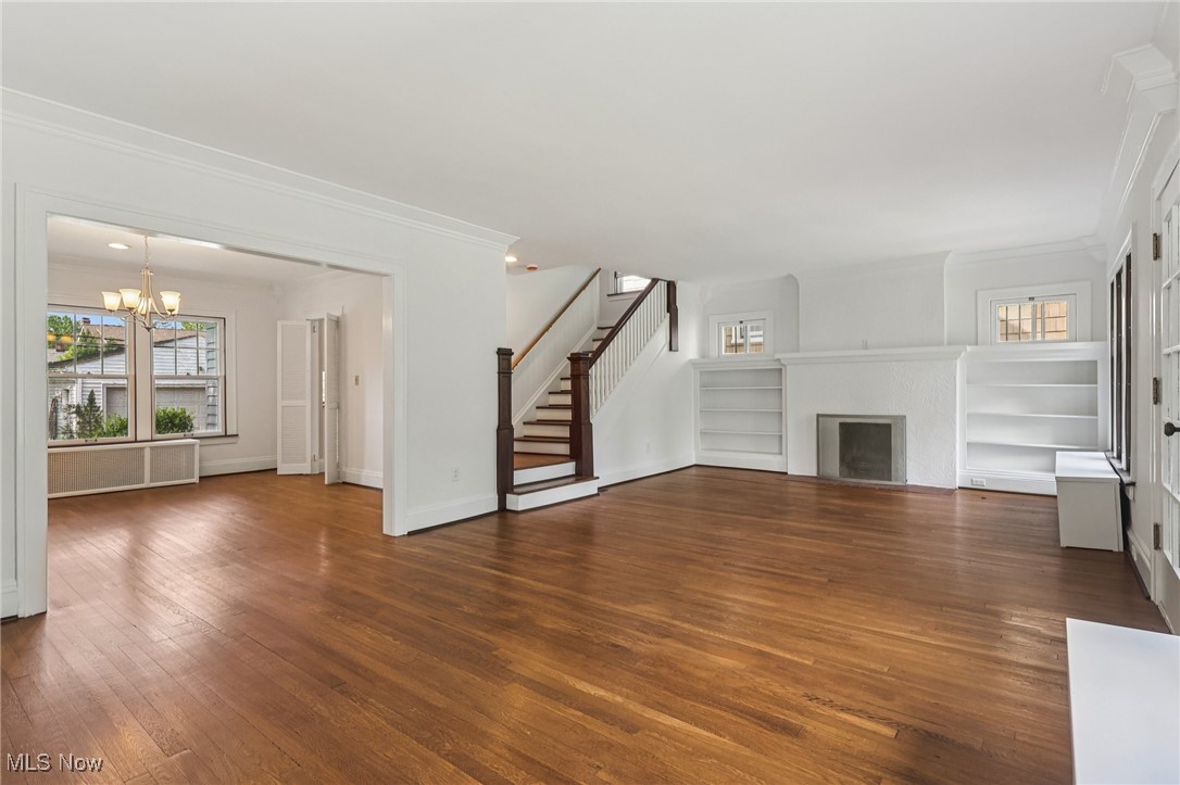3075 Scarborough Road Cleveland, OH 44118 - Photo 3 of 46 Unfurnished living room featuring a chandelier, crown molding, stairway, hardwood / wood-style flooring, and a fireplace