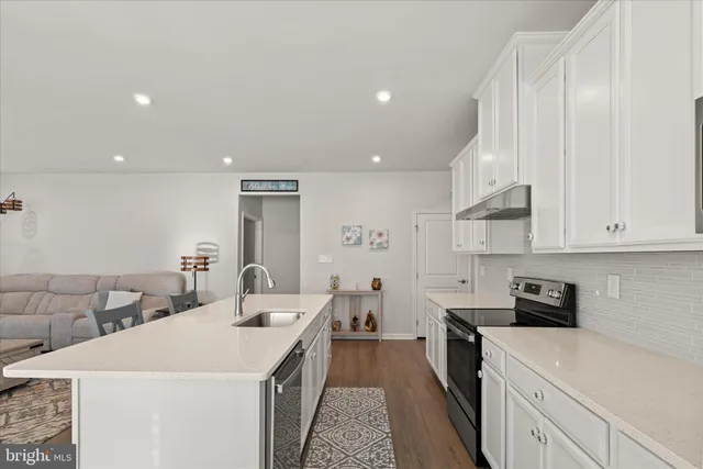 a large white kitchen with a sink and breakfast area
