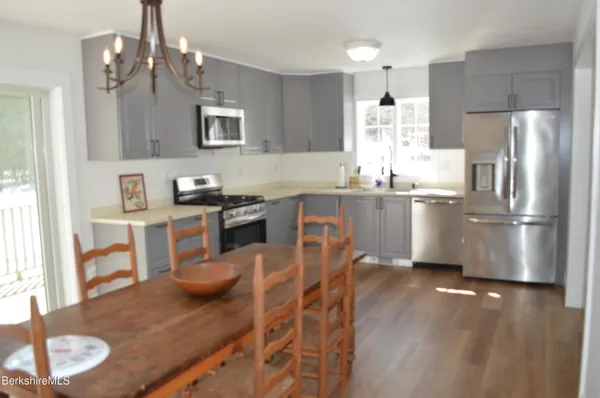 a kitchen with stainless steel appliances granite countertop a sink a stove a refrigerator cabinets and dining table