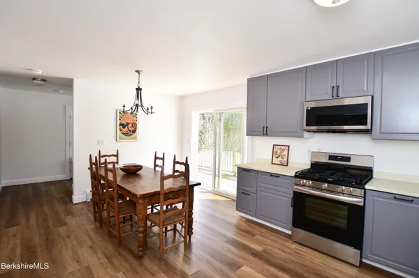 a kitchen with stainless steel appliances a stove a sink a dining table and chairs