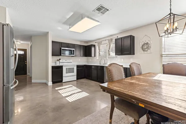 a kitchen with stainless steel appliances granite countertop a stove top oven a sink dishwasher a dining table and chairs with wooden floor