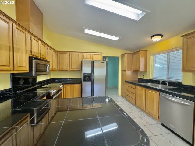 a kitchen with stainless steel appliances a stove refrigerator sink and microwave