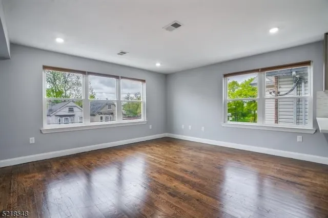 a view of an empty room with wooden floor and windows