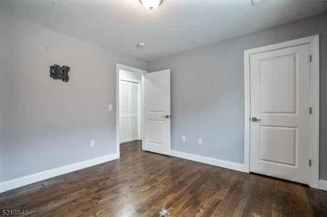 a view of an empty room with wooden floor and closet