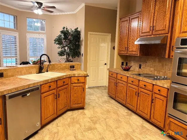 a kitchen with granite countertop a sink stainless steel appliances and cabinets