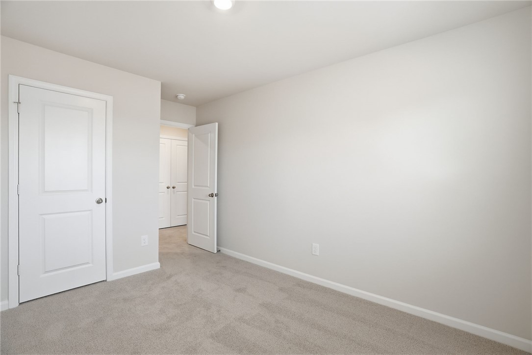 305 Lilac Loop Greenwood, SC 29646 - Photo 13 of 25 A well-lit bedroom with fresh carpet offers a pristine, move-in-ready appeal.