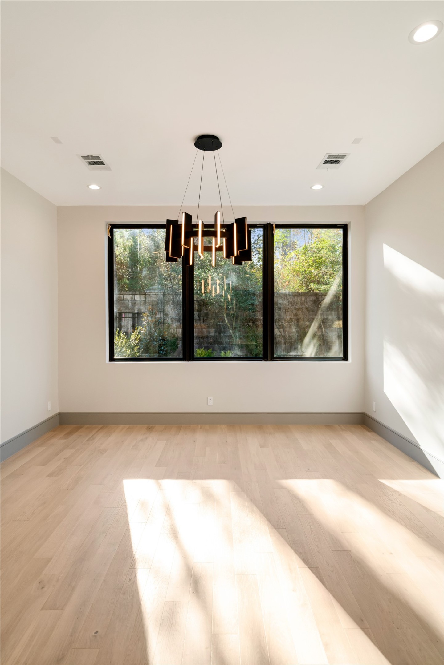 47 Pronghorn Place Spring, TX 77389 - Photo 33 of 44 This room features a modern chandelier, large windows with garden views, and light wood flooring. It's bright and airy, offering a serene atmosphere ideal for dining or relaxation.
