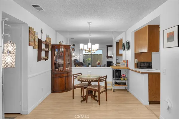 a kitchen with stainless steel appliances kitchen island granite countertop dining table chairs and a refrigerator