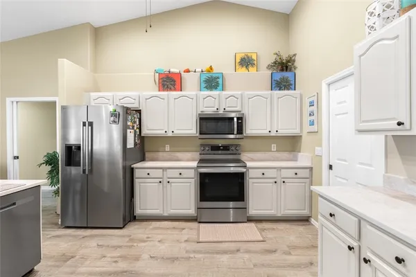 a kitchen with stainless steel appliances a stove a refrigerator and white cabinets