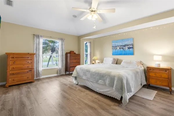 a spacious bedroom with a bed a dresser and a chandelier