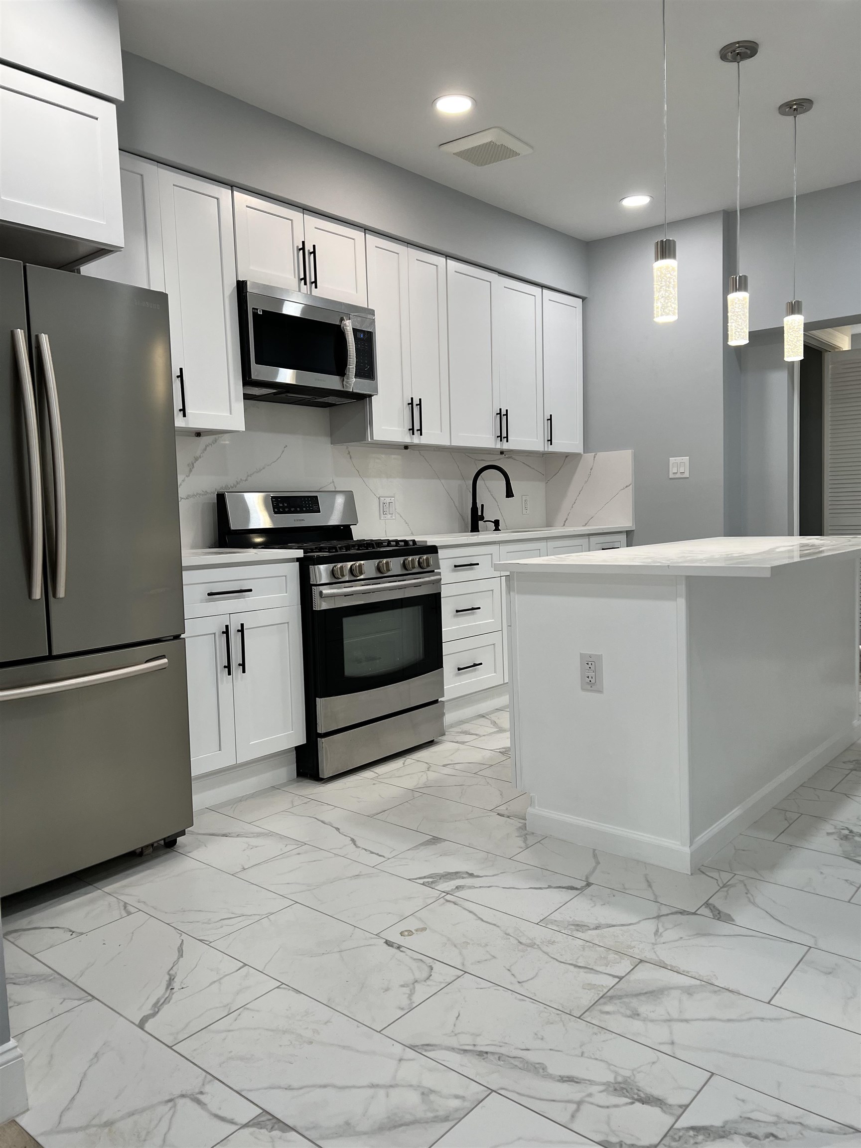 326 70th Street Guttenberg, NJ 07093 - Photo 5 of 15 a kitchen with stainless steel appliances granite countertop a refrigerator sink stove microwave and cabinets