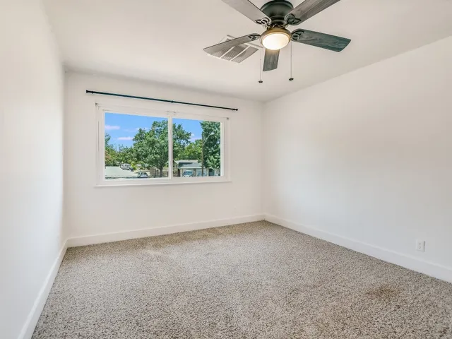 an empty room with a window and a ceiling fan