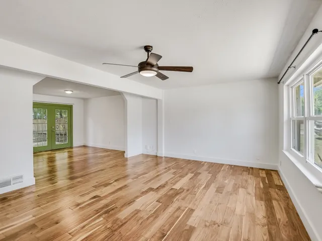 a view of empty room with wooden floor and fan