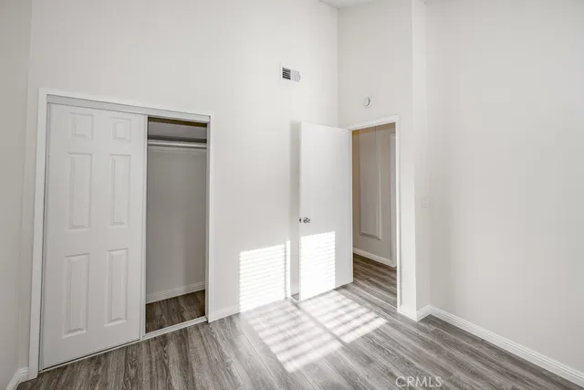 a view of an empty room with closet and wooden floor