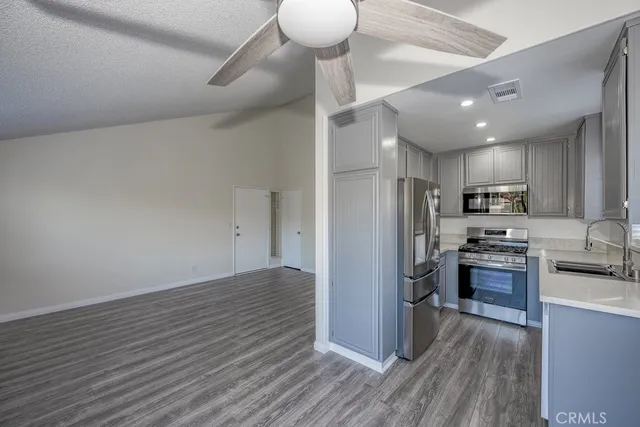 a kitchen with stainless steel appliances granite countertop a stove refrigerator and a wooden floors