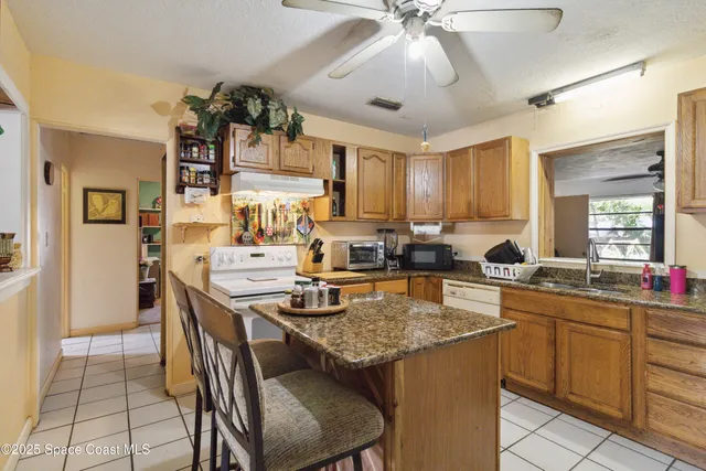 a kitchen with a stove a sink dishwasher a dining table and chairs with wooden floor