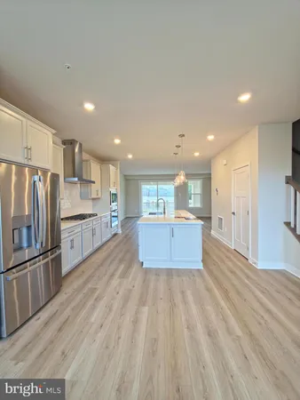 a large kitchen with stainless steel appliances kitchen island a large counter top and a refrigerator