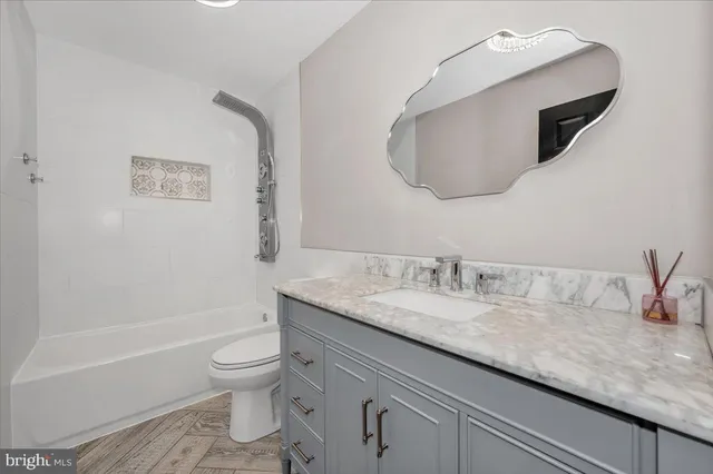 a bathroom with a granite countertop sink a toilet and a mirror