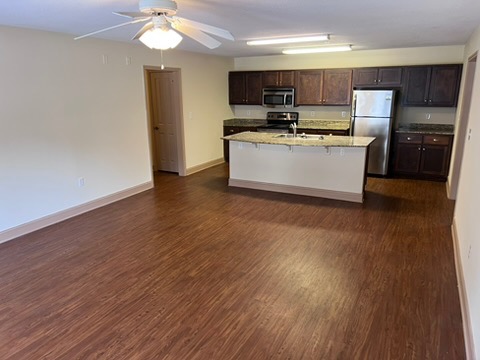 203 Kelly Road, Unit 114 Clemson, SC 29631 - Photo 9 of 37 Rich wood-look flooring stretches toward a kitchen featuring granite counters and a central island.