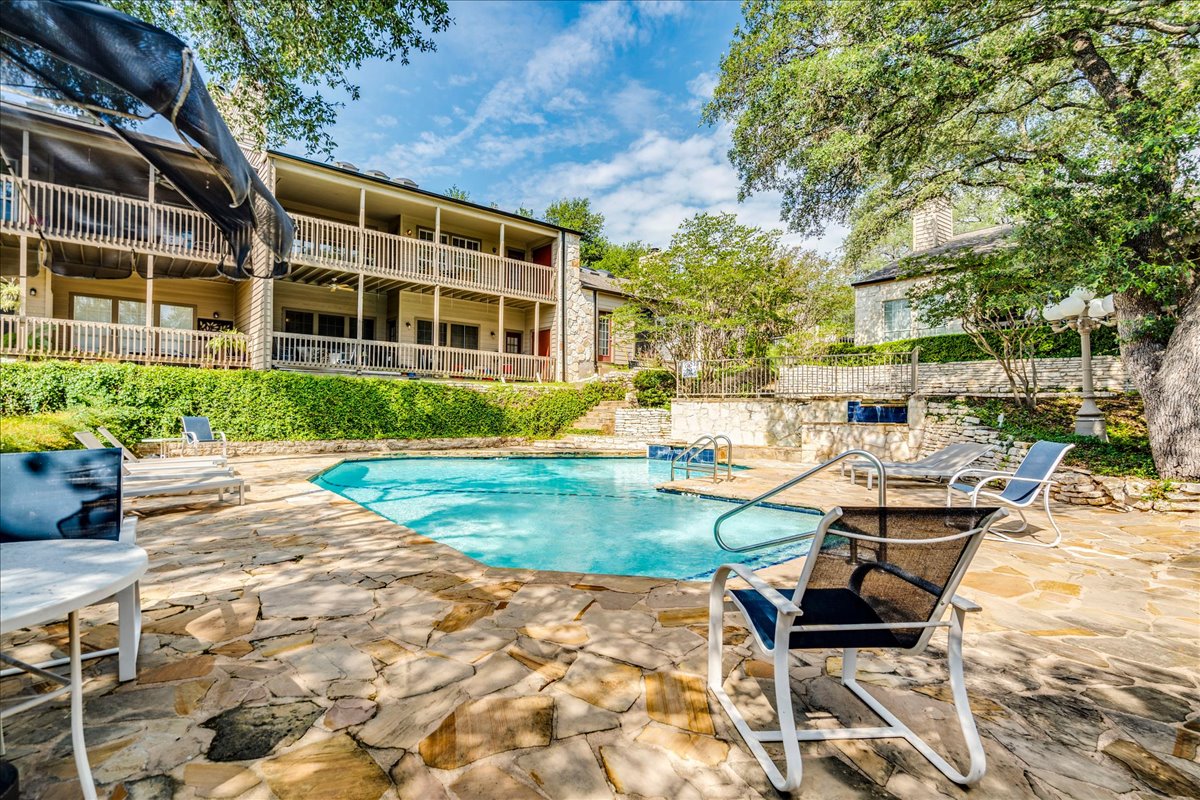3809 Spicewood Springs Road, Unit 127 Austin, TX 78759 - Photo 26 of 29 A refreshing pool with flagstone decking awaits, surrounded by lush landscaping and multi-level balconies.