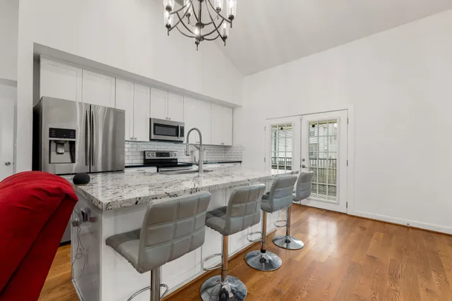 a kitchen with stainless steel appliances granite countertop a stove a refrigerator a sink a dining table and chairs with wooden floor