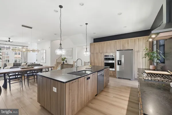 a kitchen with stainless steel appliances granite countertop a sink a stove and chairs with wooden floor