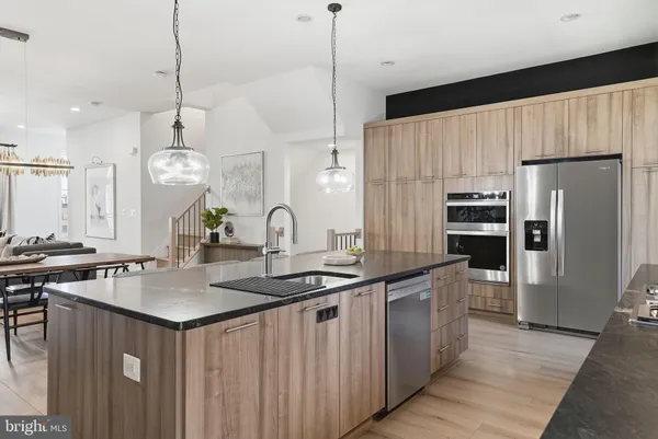 a kitchen with kitchen island a stove a sink a counter top space and living room view