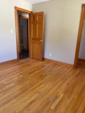 a view of an empty room with closet and wooden floor