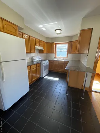 a kitchen with granite countertop a sink a stove a refrigerator a washer dryer and white cabinets
