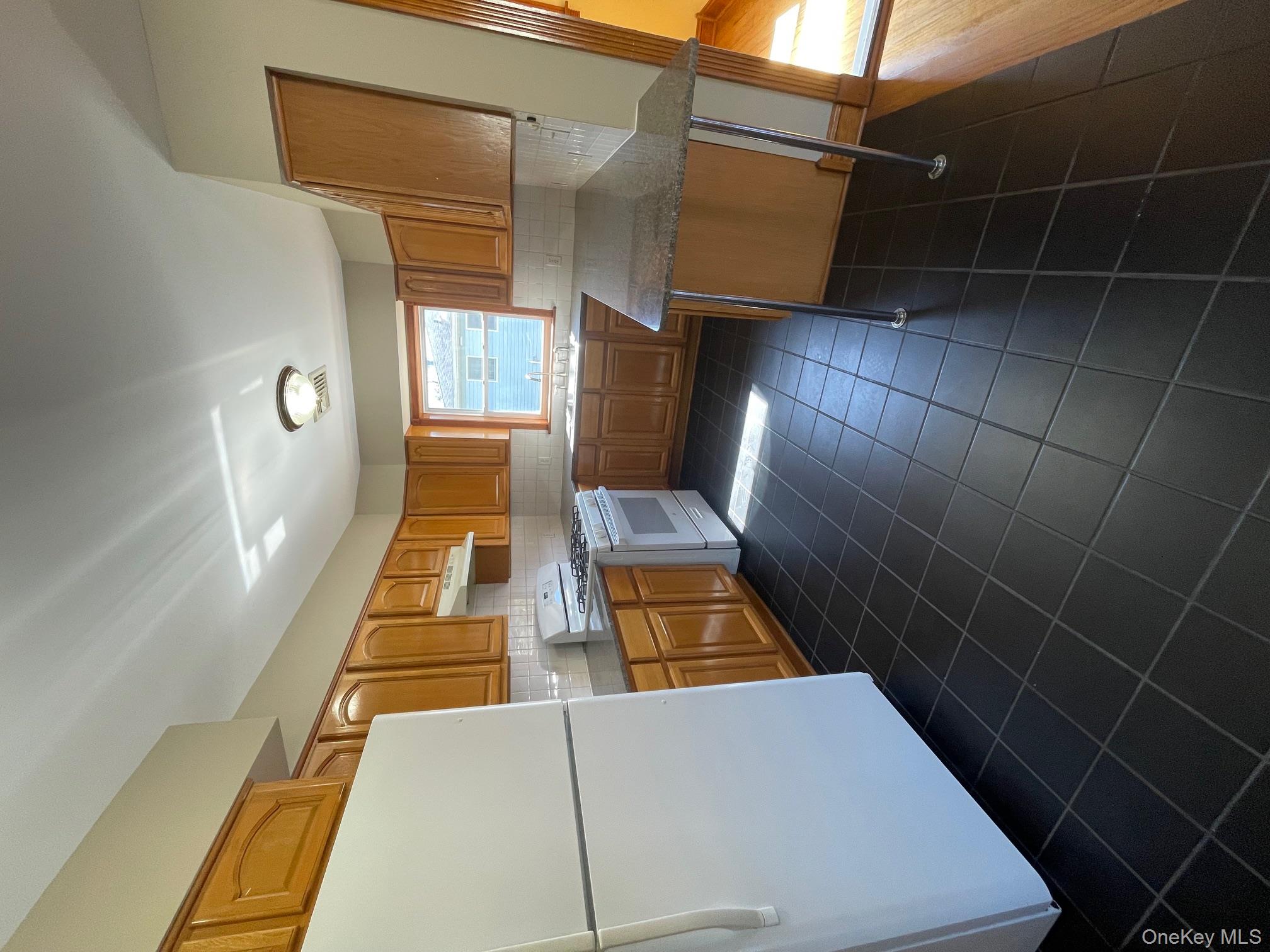57 Ashland Street, Unit 2 New Rochelle, NY 10801 - Photo 4 of 19 Kitchen featuring refrigerator, white range with gas stovetop, backsplash, dark tile patterned flooring, and range hood