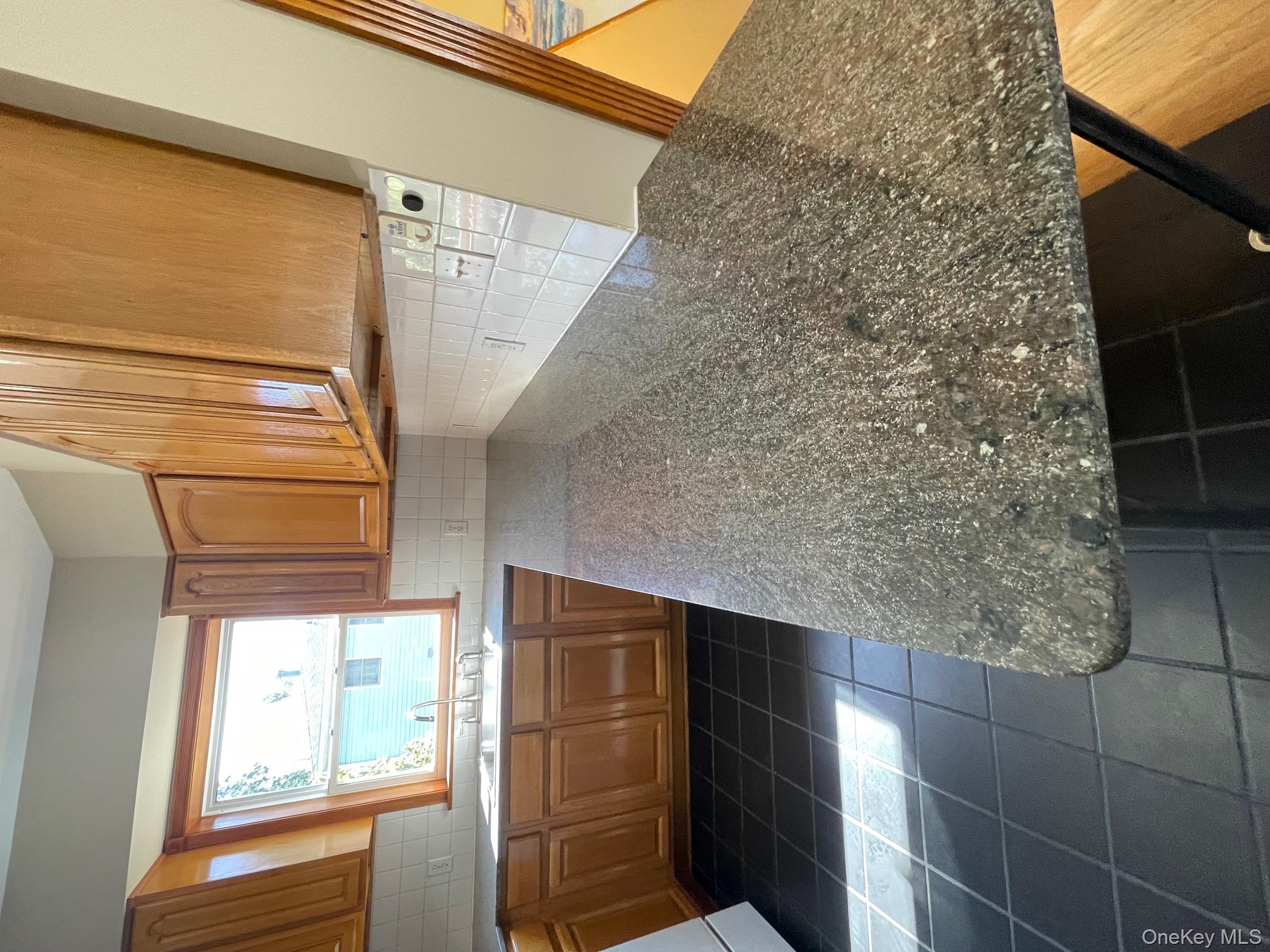 57 Ashland Street, Unit 2 New Rochelle, NY 10801 - Photo 5 of 19 Kitchen featuring brown cabinets, backsplash, dark tile patterned flooring, and a peninsula