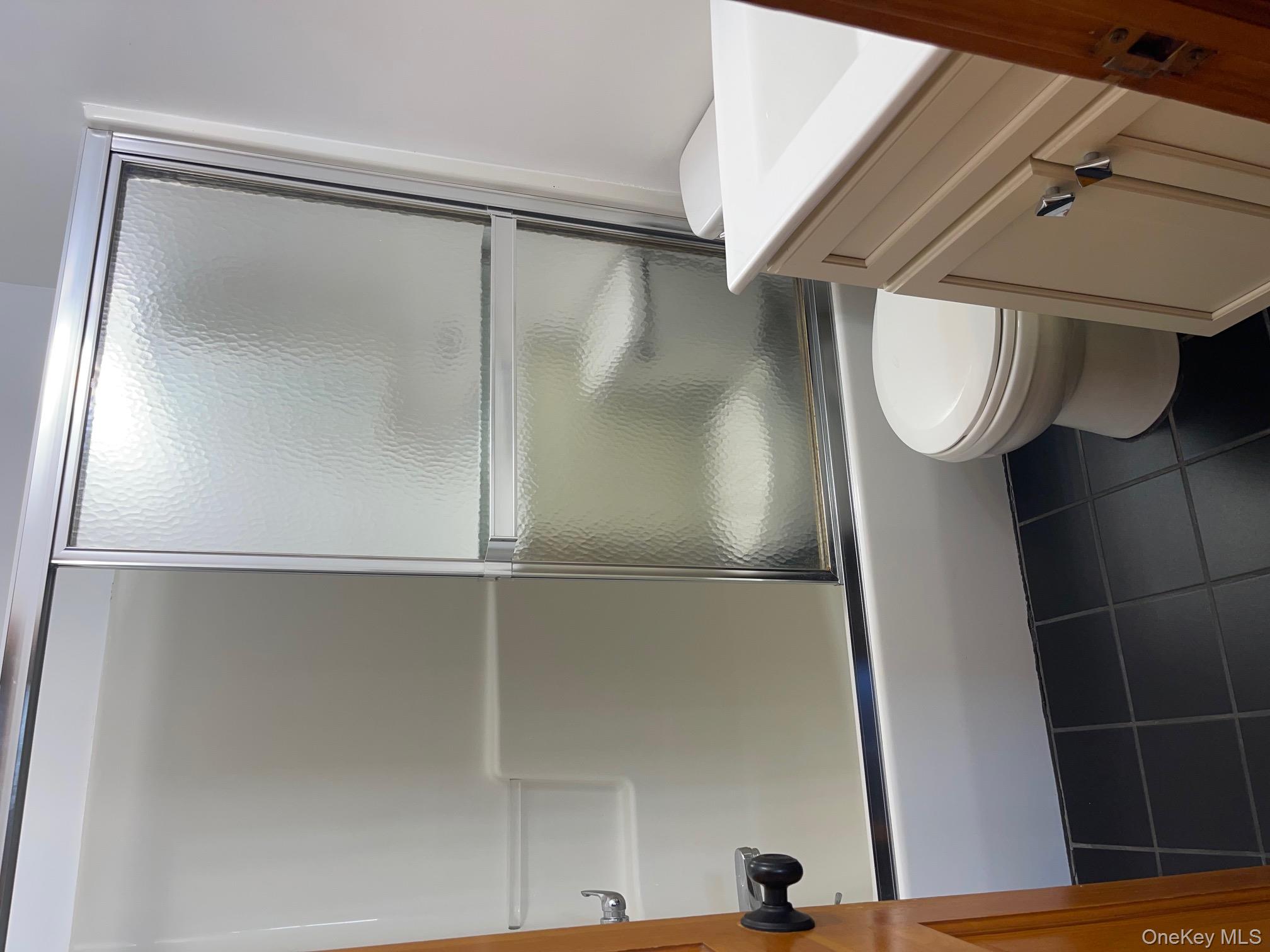 57 Ashland Street, Unit 2 New Rochelle, NY 10801 - Photo 8 of 19 Full bathroom with vanity, shower / bath combination with glass door, and dark tile patterned floors