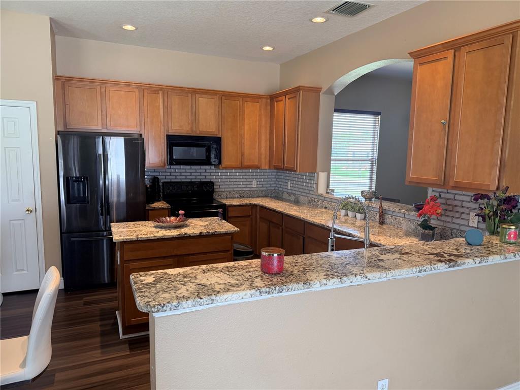 13250 Mandalay Place Spring Hill, FL 34609 - Photo 8 of 28 a kitchen with granite countertop a refrigerator and a sink