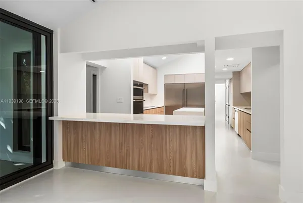 a large kitchen with stainless steel appliances kitchen island a large counter top a stove and a refrigerator