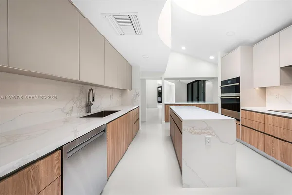 a large kitchen with stainless steel appliances kitchen island a large counter top a stove a chimney a sink and a refrigerator