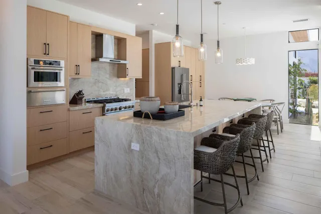 a kitchen with stainless steel appliances kitchen island granite countertop a stove a sink a dining table and chairs